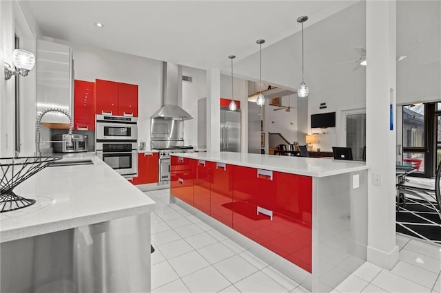 kitchen with light tile patterned floors, ceiling fan, wall chimney exhaust hood, premium appliances, and red cabinets