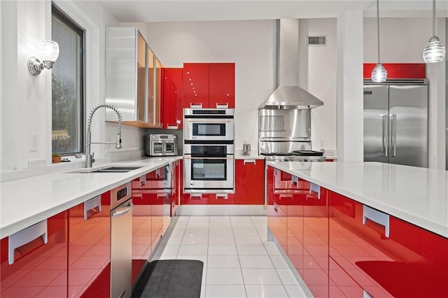 kitchen featuring red cabinetry, stainless steel appliances, light countertops, and a sink