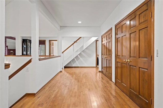 hallway featuring stairway, baseboards, and light wood-style floors