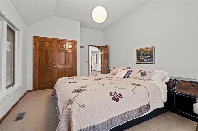 bedroom with baseboards, visible vents, vaulted ceiling, a closet, and carpet flooring