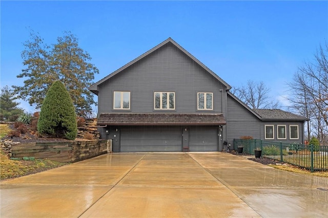 view of home's exterior featuring concrete driveway, an attached garage, and fence