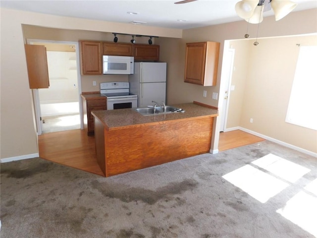 kitchen featuring a sink, white appliances, light carpet, and a peninsula