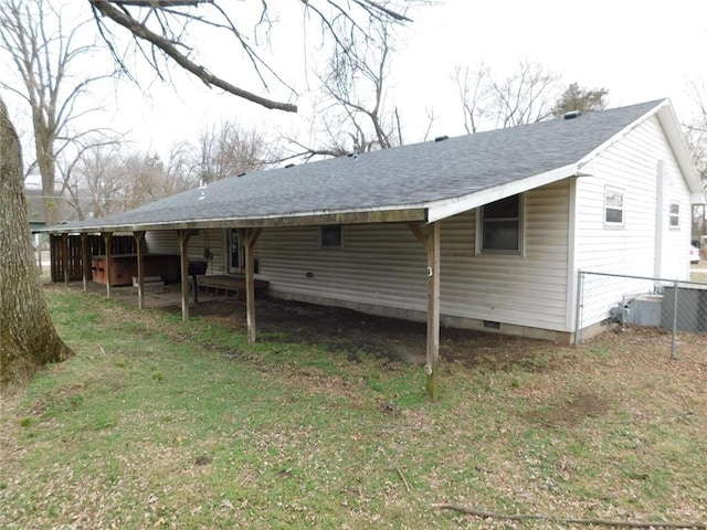 rear view of house featuring crawl space, fence, a carport, and a shingled roof