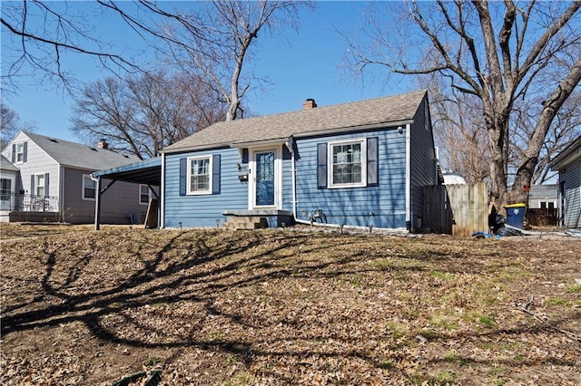 view of front of house with a carport, a chimney, and fence