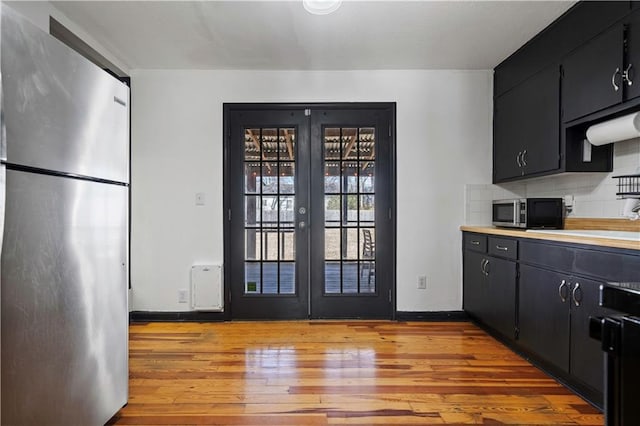 kitchen featuring light wood-style flooring, appliances with stainless steel finishes, dark cabinetry, and french doors