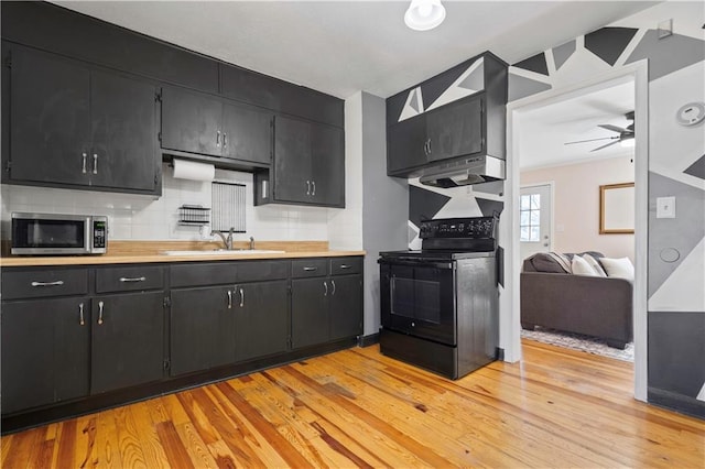 kitchen with black electric range, stainless steel microwave, a sink, dark cabinetry, and light countertops