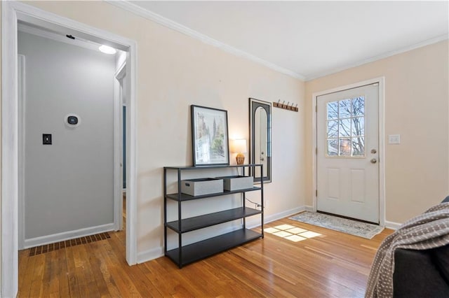 foyer entrance featuring crown molding, baseboards, and hardwood / wood-style floors