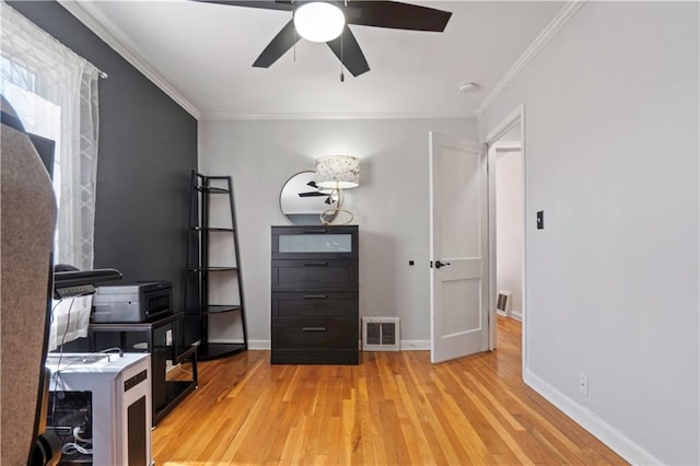 unfurnished office with light wood-type flooring, visible vents, crown molding, baseboards, and ceiling fan