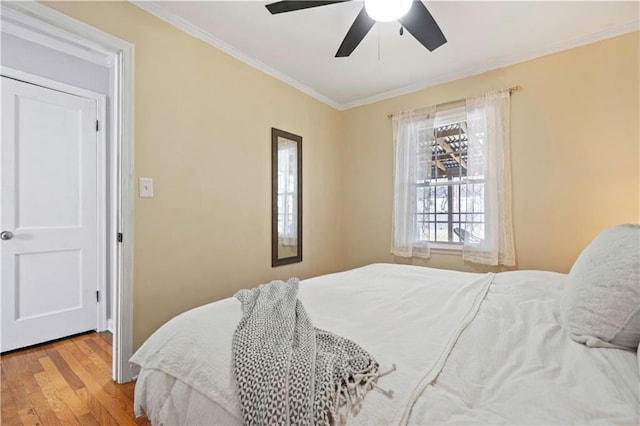 bedroom featuring ornamental molding, a ceiling fan, and wood finished floors