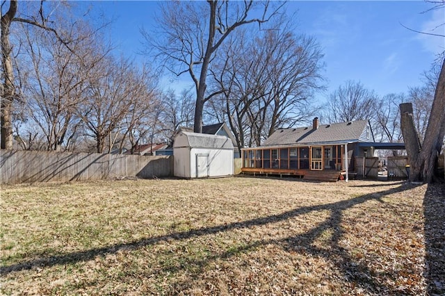 view of yard featuring an outbuilding, a shed, fence, and a sunroom