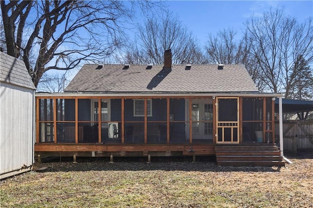 rear view of house with a chimney, roof with shingles, and a sunroom