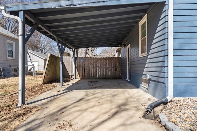 view of patio with a carport, driveway, central AC, and fence