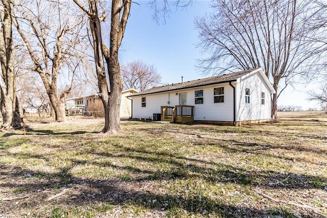 rear view of property featuring central AC unit and a lawn