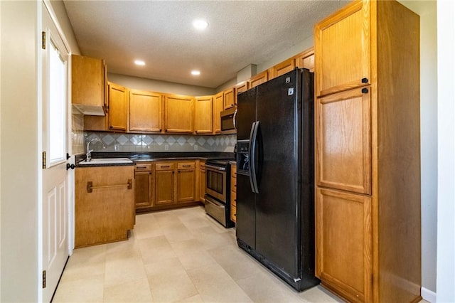 kitchen with dark countertops, decorative backsplash, appliances with stainless steel finishes, brown cabinetry, and a sink