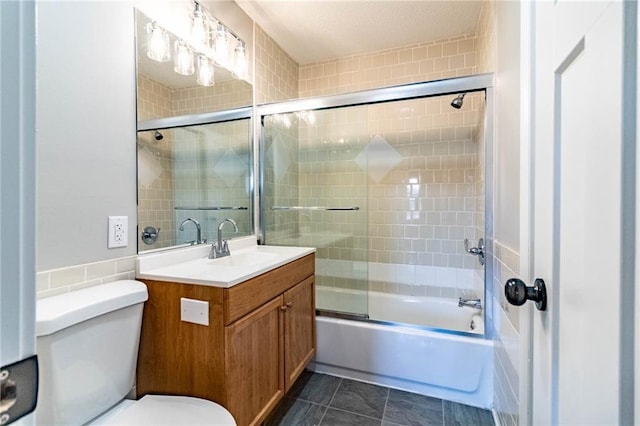 bathroom featuring bath / shower combo with glass door, toilet, and vanity