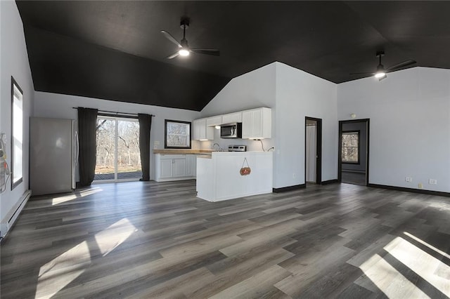 interior space featuring a baseboard heating unit, ceiling fan, open floor plan, appliances with stainless steel finishes, and white cabinetry