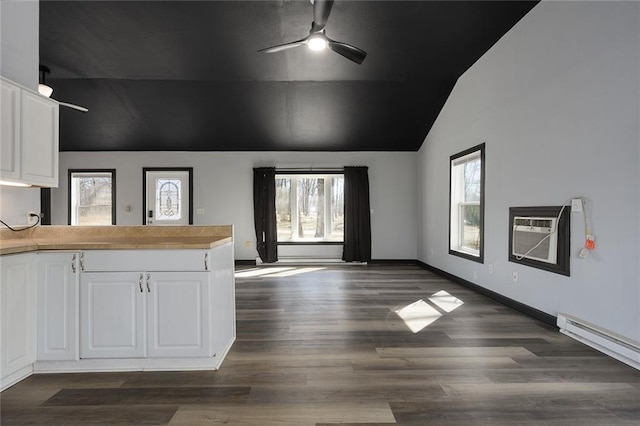 interior space featuring a healthy amount of sunlight, dark wood-style floors, a wall mounted AC, and vaulted ceiling