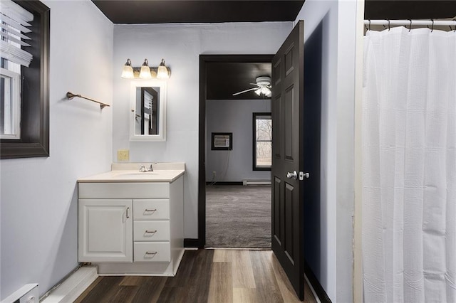 bathroom featuring a baseboard heating unit, wood finished floors, a baseboard radiator, baseboards, and vanity