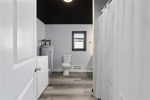 full bath featuring baseboards, toilet, washer / dryer, wood finished floors, and a baseboard radiator