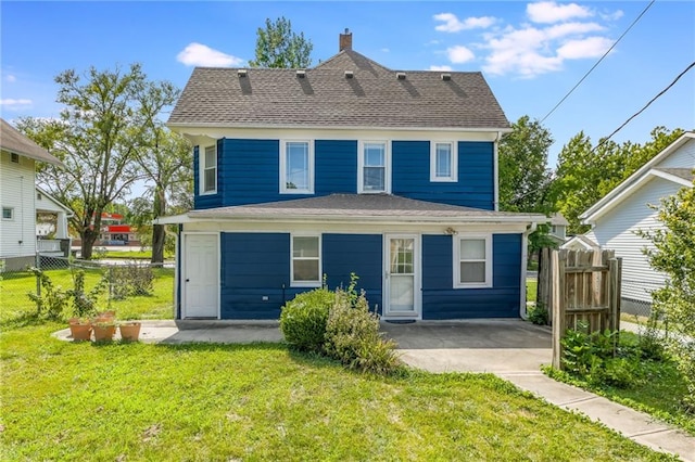 back of house featuring a patio area, a lawn, a shingled roof, and fence