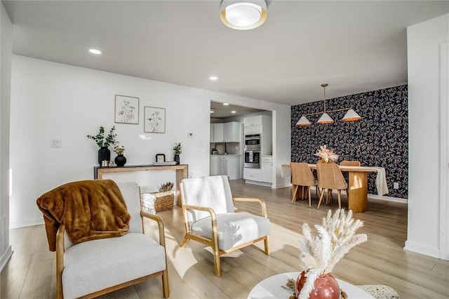 living room with wallpapered walls, light wood-style flooring, recessed lighting, and an accent wall