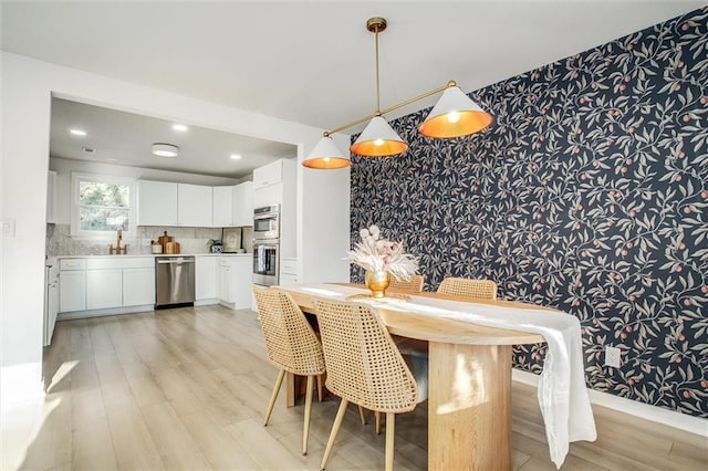 dining area featuring wallpapered walls, recessed lighting, light wood finished floors, and an accent wall