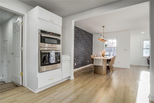 kitchen featuring a healthy amount of sunlight, double oven, and light wood-type flooring