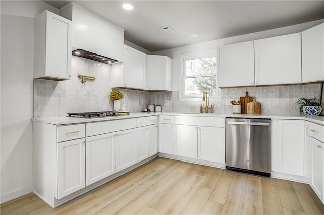 kitchen with a sink, stainless steel appliances, light wood-style floors, and light countertops