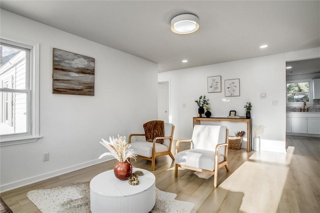 living area featuring recessed lighting, baseboards, and light wood-style flooring