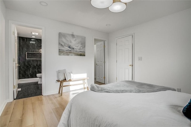 bedroom with ensuite bath and light wood-type flooring