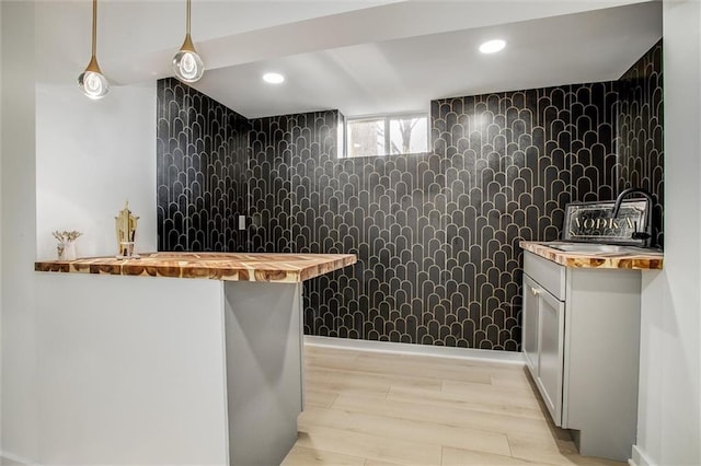 bar featuring tile walls, recessed lighting, light wood finished floors, and a sink