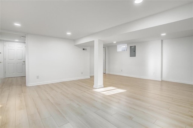 finished below grade area with electric panel, recessed lighting, baseboards, and light wood-style floors