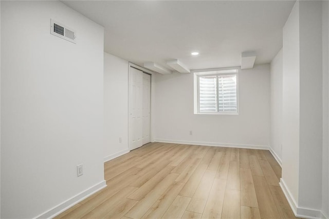 below grade area with visible vents, baseboards, and light wood finished floors