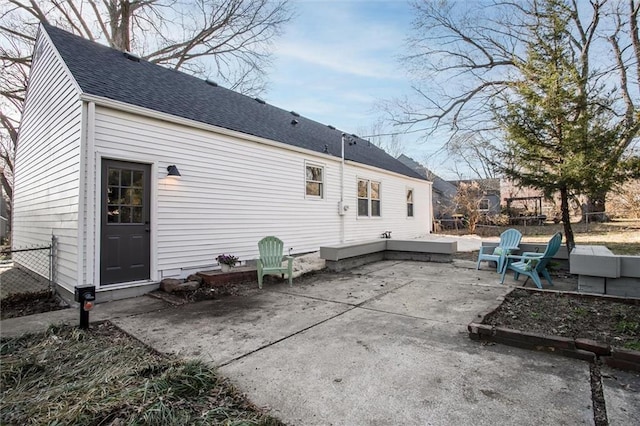 back of property featuring a shingled roof, a patio, and fence