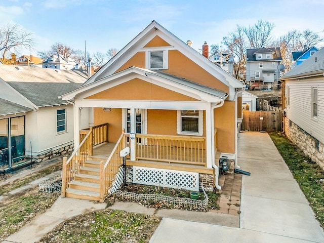 view of front of house with covered porch, fence, and stucco siding