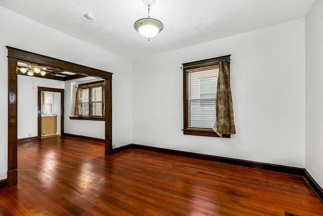 empty room featuring hardwood / wood-style flooring, baseboards, and a textured ceiling