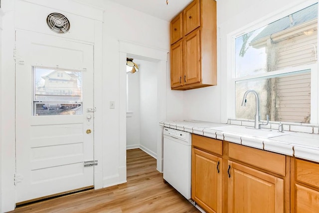 kitchen featuring a sink, tile countertops, light wood-style floors, white dishwasher, and baseboards