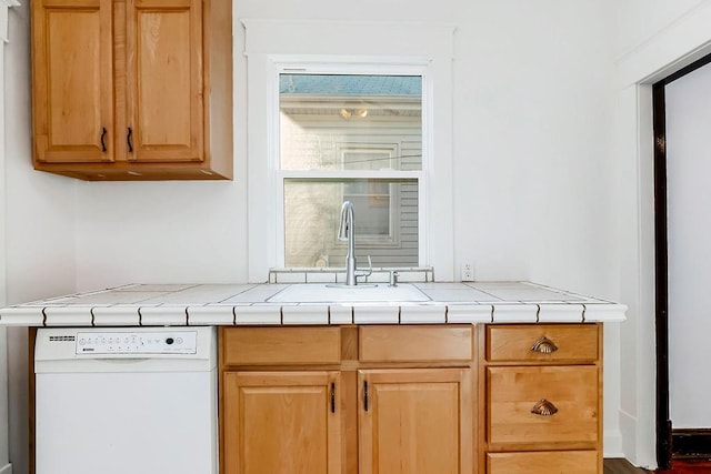 kitchen with a sink, light brown cabinetry, tile counters, and white dishwasher