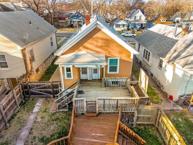 rear view of house featuring stucco siding, a fenced backyard, a residential view, and a wooden deck