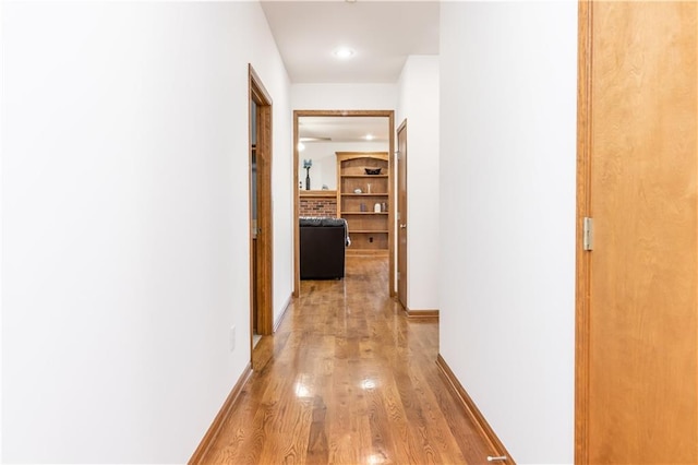 corridor featuring light wood-style flooring and baseboards