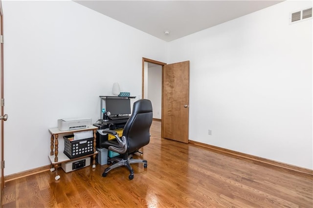 office space featuring visible vents, baseboards, and wood finished floors