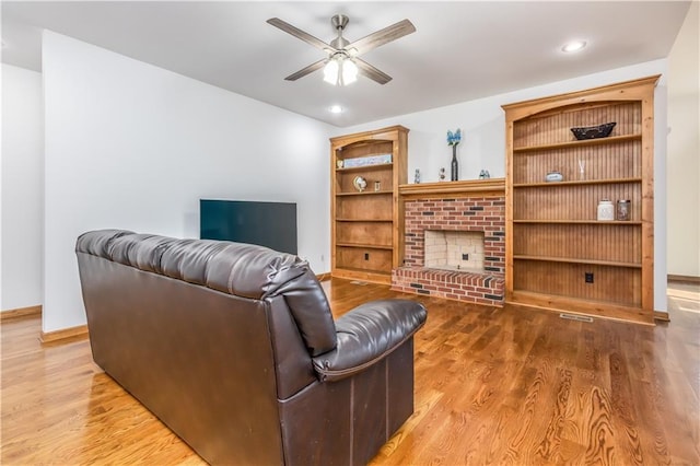 living room featuring baseboards, ceiling fan, recessed lighting, a fireplace, and wood finished floors