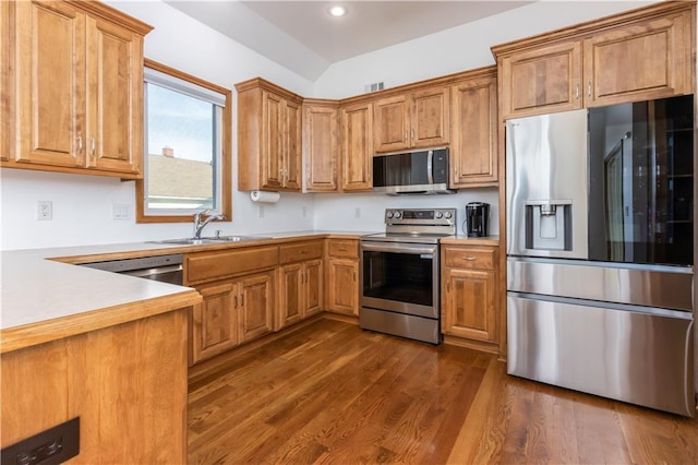 kitchen featuring a sink, brown cabinets, appliances with stainless steel finishes, and dark wood-style flooring