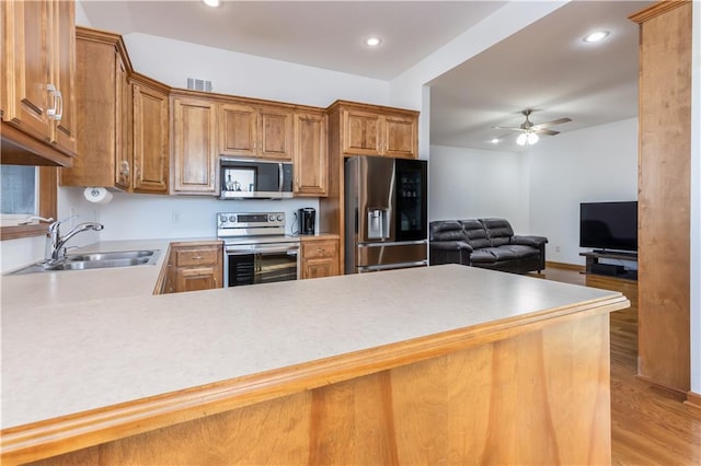 kitchen with a ceiling fan, visible vents, a sink, appliances with stainless steel finishes, and brown cabinets