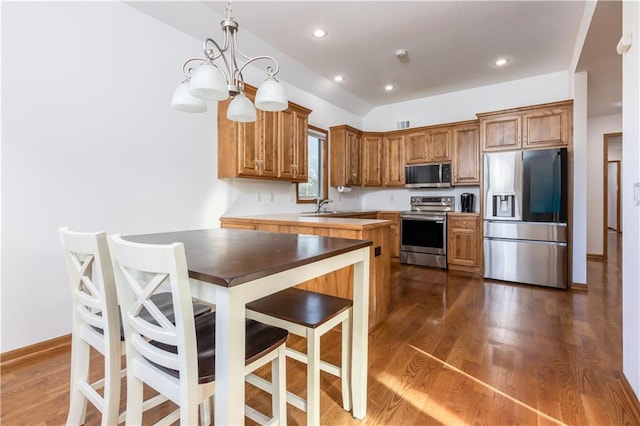 kitchen with an inviting chandelier, dark wood-style floors, appliances with stainless steel finishes, and a sink