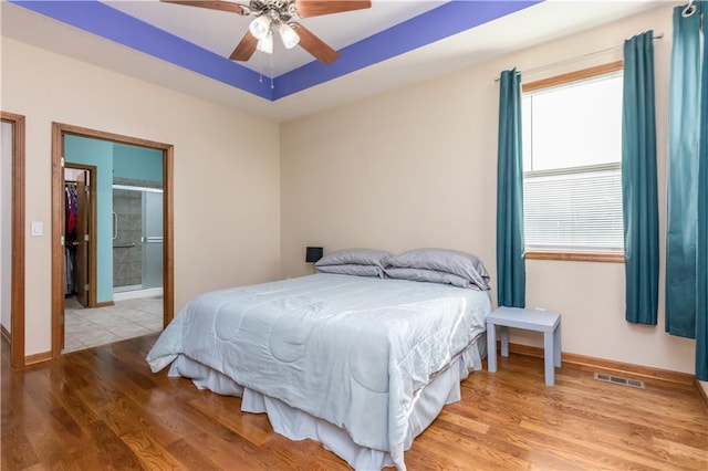 bedroom with visible vents, a raised ceiling, light wood-style floors, and baseboards