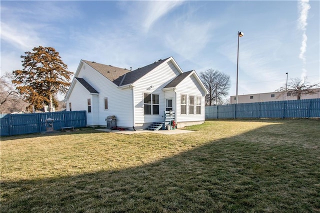 back of property featuring entry steps, a lawn, and a fenced backyard