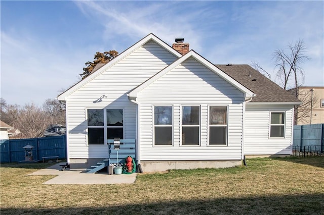 back of property featuring a patio area, a lawn, a chimney, and fence