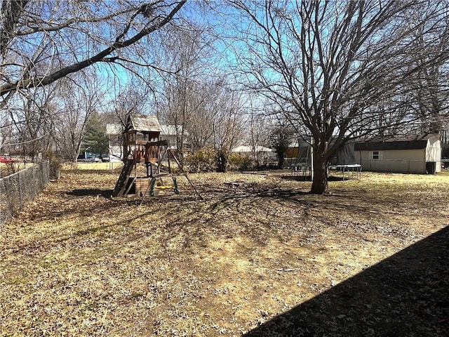 view of yard featuring a playground, a trampoline, and fence