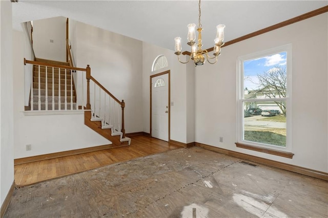 foyer entrance with visible vents, wood finished floors, an inviting chandelier, baseboards, and stairs